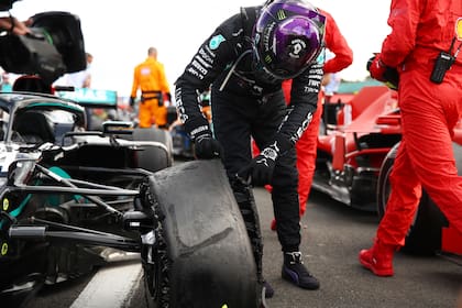Lewis Hamilton revisa cómo quedó su neumático delantero izquierdo tras bajarse de su auto al final del GP de Gran Bretaña.