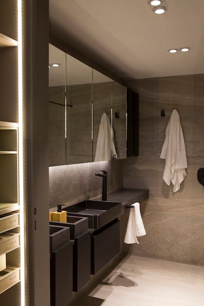 La grifería y los artefactos en negro mate aportan un carácter fuerte y distintivo. El diseño del mobiliario, con líneas rectas y volúmenes flotantes, garantizan practicidad sin perder sofisticación. Artefactos SHHH Bi (Idea Iluminación).