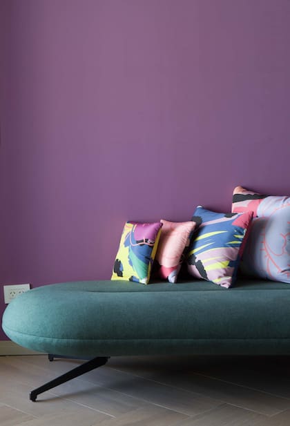 El violeta de la pared (Colorín) en fuerte contraste con el tapizado del soft seating y los almohadones.