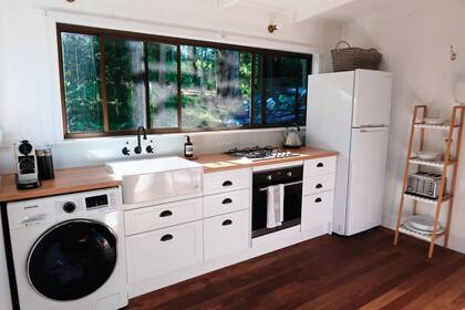 La cocina sigue la paleta de la casa: madera en la mesada y blanco y negro en el amoblamiento y los artefactos.