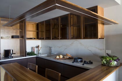 Superficies de mesada, pileta integrada y revestimientos en Puraprima Ónix White (De Stéfano, trabajados por Artecnia Mármoles). Las hornallas Pitt Cooking emergen y contrastan con el plano claro.