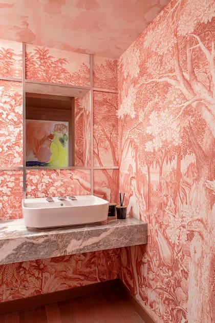 La mesada de mármol 'Fior di Pesco' (De Stefano) retoma tonos del mural entelado ‘Paraíso Rojo’ (Edición Particular). El espejo crea profundidad en medio de la perfilería cromada (Shawer).