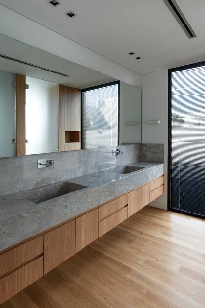 Los baños tienen mesadas de mármol (Tundra Grey), vanitorys enchapado en roble y griferías (Dominic New de FV). En este, piso de madera natural de roble (no multiestrato).