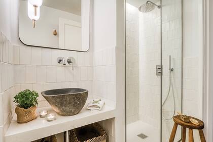 En el baño, revestimiento cerámico, espejo (Zara Home), bacha de piedra (Tikamoon) y lámparas (Aroma del Campo).