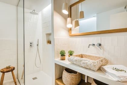 Baño en suite con espejo enmarcado hecho a medida, bacha de mármol (Tikamoon) y lámparas de cerámica diseñadas por Farré & Costa.