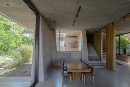 Una mesa de madera marca el sector del comedor, iluminada con artefactos empotrados y colgantes.