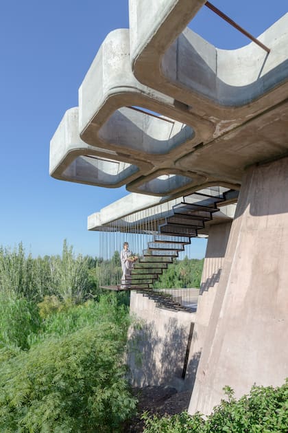 Prefabricada e instalada después de hormigonar, la escalera externa de hierro y metal desplegado queda suspendida gracias a tensores empotrados en la losa.