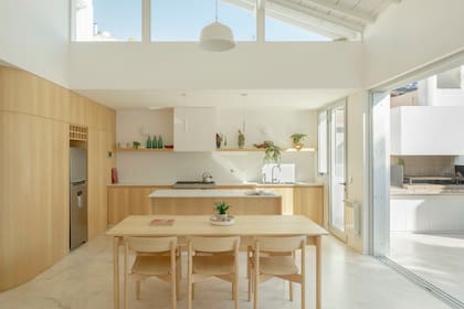 Net. El gran mueble de madera aloja una despensa y el nicho para ubicar la heladera. El ventanal se oculta dentro del muro, permitiendo una apertura total al patio transformado en jardín con parrilla.