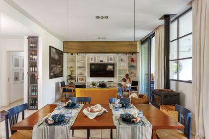 Mesa de timbó (Mesopotamia) con caminos, individuales y servilletas de Lado Blanco Home y vajilla de Salazar Casa. Lámpara colgante ‘Grisín’, en bronce (La Feliz). Biblioteca (Nicho).