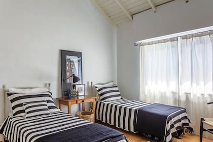 En el cuarto de huéspedes, camas de hierro con cubrecamas rayados y, en el medio, fotografía de Gloria García Fernández.