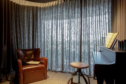 Sillón de cuero, banquito antiguo y piano Yamaha.