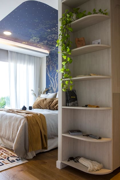 Una estantería le suma espacio de guardado a la antesala del dormitorio. Las cortinas de gasa de algodón son de confección propia.