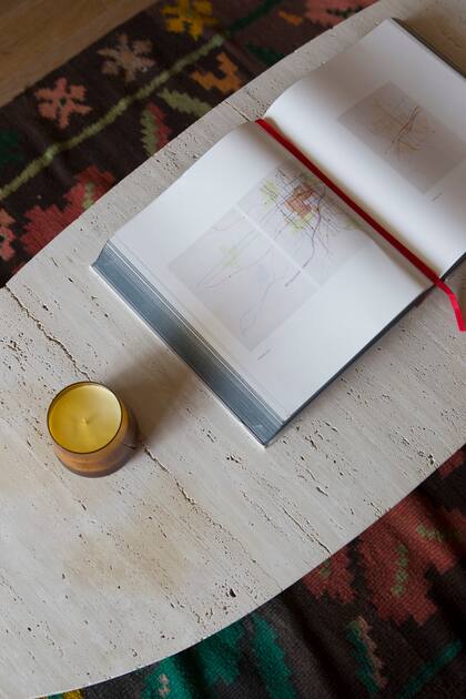 En una doble capa de texturas, alfombra tejida y mesa ovalada de piedra.