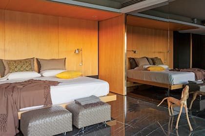 Al costado de la cama se encuentra el vestidor con puertas de vidrio fumé. Lámparas de brazo flexible (Griscan). Butacas (Flexform).