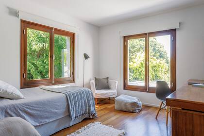 Cama (Rosen) con mantas grises (Masai Deco), cortinas roller (Hunter Douglas), lámpara de pie (San Isidro Luz) y sillón ‘Gervasoni’ (Lebon House). Los cuartos de la planta alta tienen pisos de lapacho.