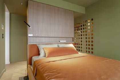 El verde de las paredes ensalza los tonos durazno-dorados de la ropa de cama (Ramos Generales). Cama (Urbano Estudio). Lámparas de pie (Idea Iluminación).