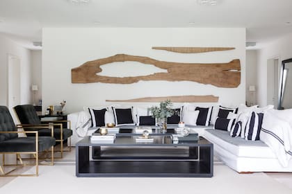 Sobre la pared de 4 metros, escultura de nogal (Mono Giraud). Sillón en L de lino arpillero, almohadones de linos fino y arpillero (todo de 11.11 Home & Deco).