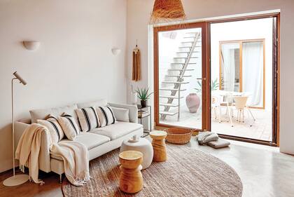 Sobre el sillón, almohadones comprados en Marruecos. Los taburetes de madera y la mesa de centro ‘Pebble’ en color cemento son del estudio de interiorismo catalán MIV Interiores.
