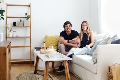 Tomás y Dominique en el living con un sillón en L con funda de tussor y almohadones de colores.