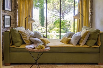 Perfectamente adaptado a la ventana que se proyecta, el sofá es una maravilla para recostarse a leer o descansar con vista al jardín.