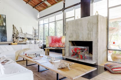 El living ocupa el espacio central frente al hogar de hormigón que, cuando no se usa, les da marco a las obras de Berna, como la caja de acrílico con peces que se ve en esta imagen.