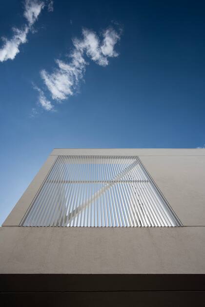 La planta alta está revestida en un revoque texturado blanco (Tarquini), que la hace verse como un volumen puro y etéreo.