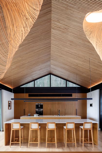 La parte superior del mueble de madera contiene las rejillas del aire acondicionado. Banquetas “Gunta Collection”, de Leone Loray y Fontenla.