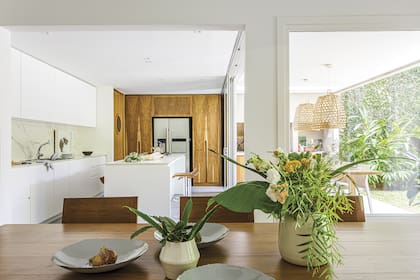 Una gran alacena de petiribí contiene la heladera e incorpora una puerta con ojo de buey que comunica con el garage. Aberturas de PVC (Welttechnik).