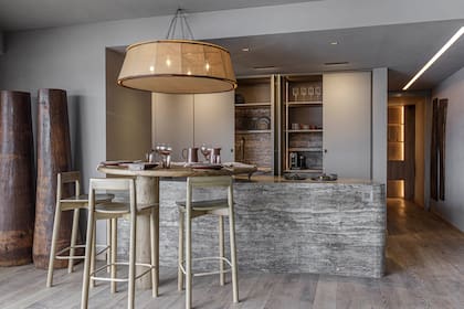 La cocina con una gran mesada que continúa en una mesa redonda de madera