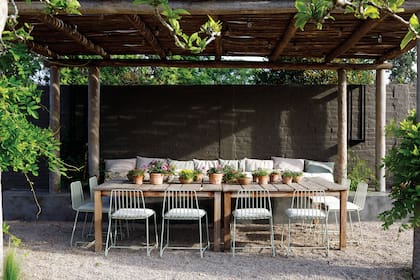 De un lado de la mesa, sillas de hierro verdes (Virginia Lagos) y, del otro, un banco corrido de cemento alisado, cubierto con almohadones.