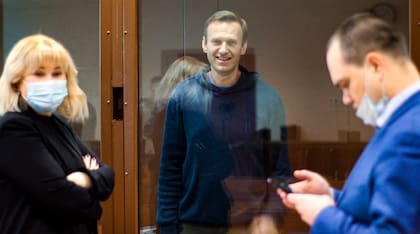 Foto del 16 de febrero de 2021, en la que el líder opositor ruso Alexei Navalny sonríe mientras habla con sus abogados Olga Mikhailova y Vadim Kobzev durante una audiencia por cargos de difamación, en Moscú, Rusia. (Servicio de Prensa del tribunal de distrito de Babuskinsky vía AP, Archivo)