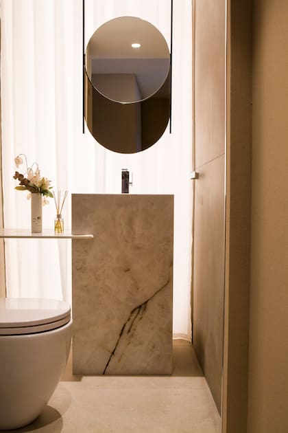 Piso y paredes en porcelanato 'Adeona Antiq Duo' (San Lorenzo Design). Mesada y tótem de Neolith 'Himalaya' (De Stefano). Grifería (Novum). Sanitario 'Fontana' corto (Ferrum). Detrás del espejo, se aplicó una placa de acrílico con LED.