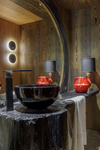 El inmenso espejo con marco de madera viene de la casa de la diseñadora. Mesada de madera quemada (Enigma). Velador (Damax).