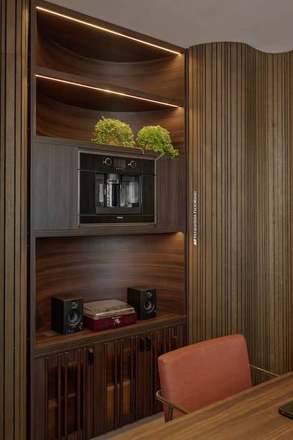 La cafetera (Teka) y el sistema de música (Todo Música) son clave en este ambiente de confort. Mueble en melamina Merlot con interesantes detalles curvos y en la puerta inferior (Halesa Estudio by Casa Leiro).