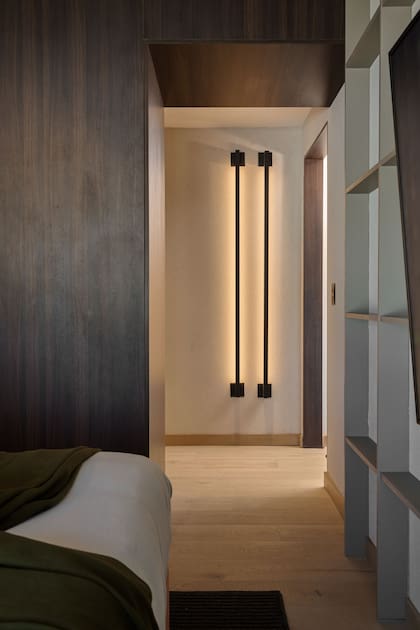 Dos luminarias verticales con luz rasante (IDEA) realzan el paso del dormitorio al vestidor y el baño en suite.