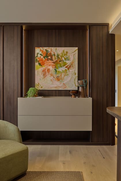 El mueble flotante y los placares en melamina Merlot (FaPlac) con cantos en madera maciza, diseño de Halesa realizdos por Casa Leiro. Obra “Esmeralda”, de Sofía Mastai (Diderot.art).