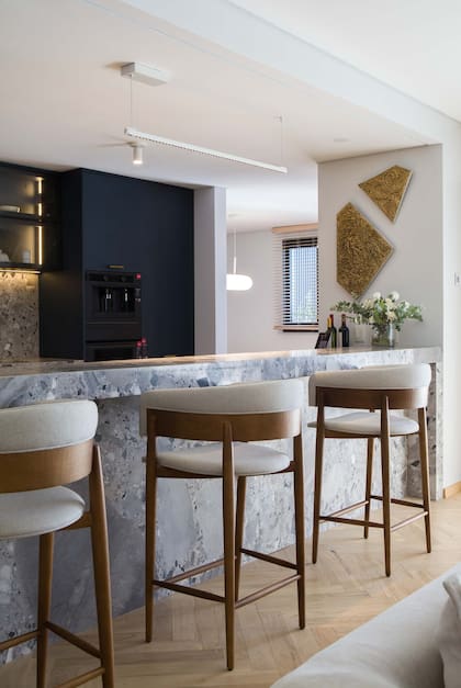 Acompañan la barra de mármol “Fior Di Pesco Carnico" (De Stefano) hecha por Ragomar taburetes "Clam" (Fontenla), en lenga y tapizado con tela rústica. Pisos de madera Patagonia Flooring.
