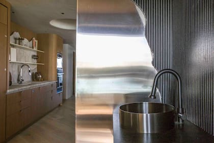 Mesada ingletada en granito “Negro Bali”, terminación en leather ranurado (De Stefano). Grifería (RV). Bacha (Ferrum). El ranurado del revestimiento negro dialoga con el acero que rompe las líneas rectas.