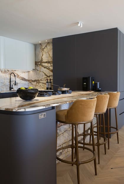 El terciopelo camel de las banquetas se engaman con las vetas de color del mármol en la cocina.