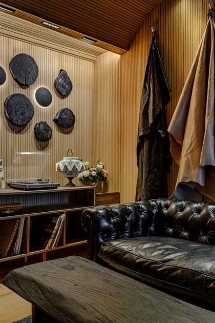 Mueble de musica en melamina 'Nogal Terracota' de Faplac (Concepto muebles). Leticia le sumó a la pared troncos quemados con su forma natural. Un tronco aparece también en la mesa, que puede usarse como banco (Enigma).