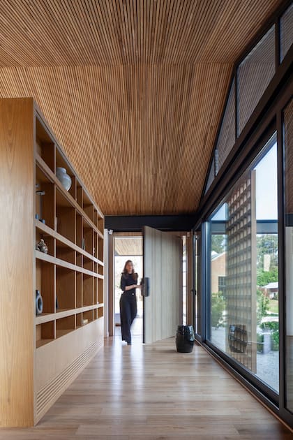 La estantería empotrada (Leone Loray y Fontenla) marca el recorrido al área pública de un lado y aloja la tele del otro. El enrejado de la parte inferior absorbe el aire acondicionado, recurso que se usó en diversos muebles de la casa.