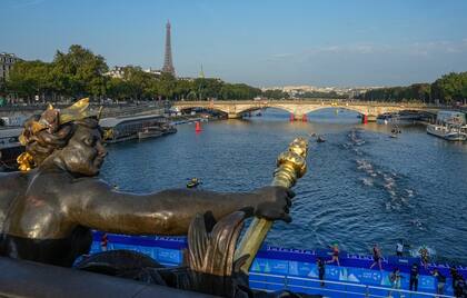 Foto del jueves 17 de agosto del 2023, atletas saltan y nadan en el río Sena cerca del puente Alexander III en la primera etapa del evento de prueba del triatlón para los Juegos Olímpicos 2024. (AP Foto/Michel Euler)