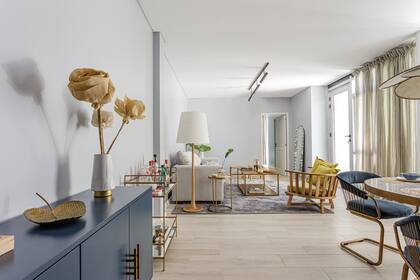 Junto al sillón de pana, lámpara de pie (Flo’s Market). Mesa de arrime con tapa de vidrio y baja ‘Lagarto’ con estructura, base y tapa de hierro dorado (Mesopotamia). Sillón individual y espejo apoyado en la pared (Wood Market). Alfombra (Rugit).