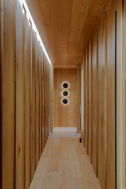 Piso, paredes y cielorraso en roble Terapak y pinotea natural Proa (Patagonia Flooring). Para ayudar a la percepción visual, se usaron luminarias decorativas (Studio Luce Aplique Bonwe) aplicadas en pared para guiar el recorrido por el espacio. La iluminación arquitectónica -que se proyectó por la arquitectas Emilia Cappiello y Diana Portillo- toma forma colocándose perfiles lineales horizontales Abo Uni y verticales Lausi V de la marca Idea.
