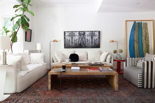 Foto en blanco y negro de Ezequiel Rohr y, parado, cuadro de Carlos Taquini. Sillón con funda rayada (Hermanas Caradonti). Mesita laqueada en rojo modelo ‘Cilindro’ (Nisla Estudio). Alfombra (Casa Sixta). Mesas ratonas en pergamino (Harturo)