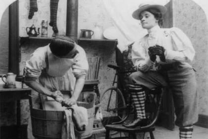 Fotografía satírica que retrata a una mujer observando a un hombre hacer la colada