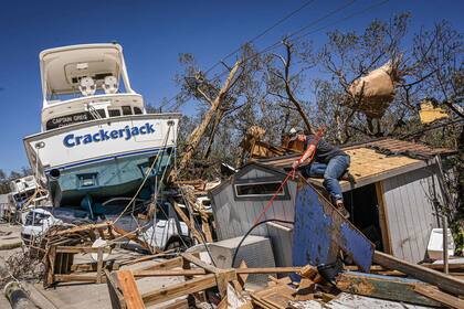 La gente limpia los escombros después del paso del huracán Ian en Fort Myers Beach, Florida, el 30 de septiembre de 2022. El huracán Ian provocó marejadas ciclónicas potencialmente mortales y dejó un territorio desconocido y varios muertos 