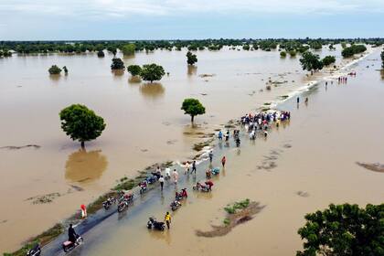 La gente camina a través de una inundación después de las fuertes lluvias en Hadejia, Nigeria, el 19 de septiembre de 2022. Nigeria está luchando contra las peores inundaciones en una década.