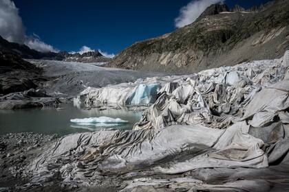 Esta fotografía tomada cerca de Gletsch, en los Alpes suizos, el 8 de julio de 2022 muestra espuma aislante que cubre una parte del glaciar del Ródano para evitar que se derrita junto a su lago glacial, formado por el derretimiento del glaciar debido al calentamiento global. - El glaciar del Ródano ha sido seleccionado entre diez glaciares de todo el mundo para ser monitoreados por cámaras de lapso de tiempo de alta resolución como parte del proyecto Planet Watch lanzado por la empresa francesa de soluciones de imágenes digitales Enlaps, que ayuda a documentar y medir el impacto del calentamiento global.