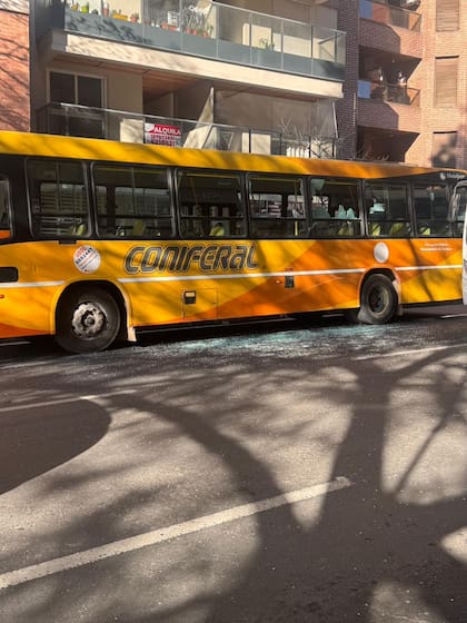 Fragmentos de vidrio en la vereda junto al colectivo dañado